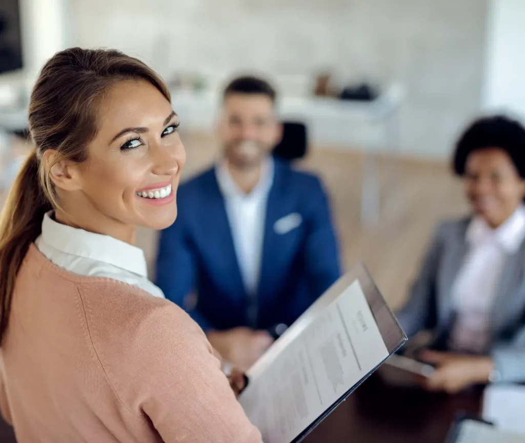A smiling HR professional holding a resume during an interview, illustrating what human resources do to unlock your team's full potential with C2 Essentials.